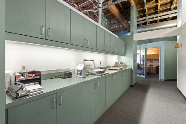 wall of upper and lower cabinets, some office supplies on counter